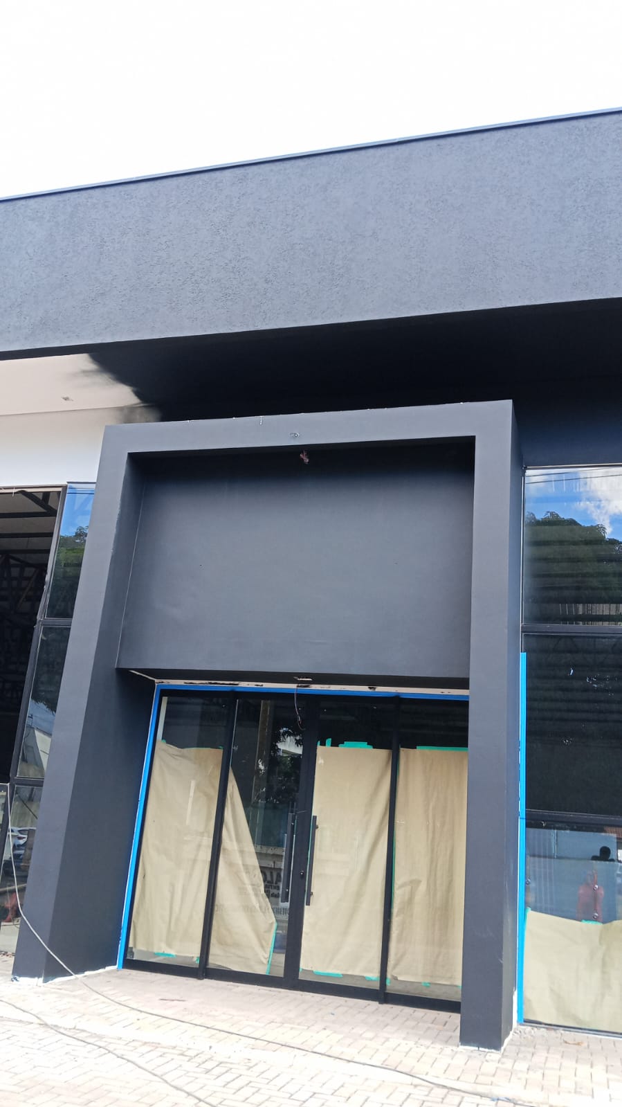 Fachada comercial pintada em cinza-chumbo com vidraçaria moderna